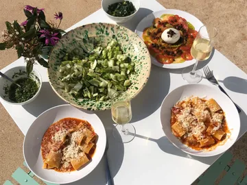 Teller mit Pasta, Salat und Getränke auf einem Tisch.