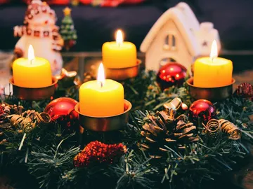 Fünf brennende Kerzen schmücken einen Adventskranz.