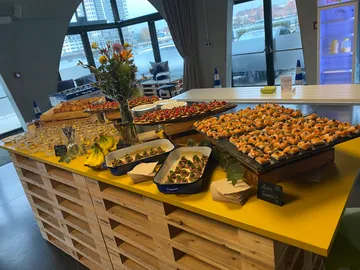 Buffet aus Snacks und Gerichten auf einem gelben Tisch.
