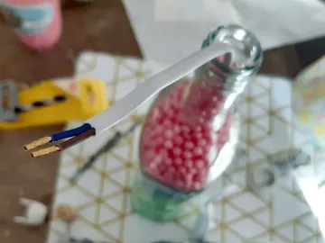 A cable sticks out of a glass bottle with pearls.