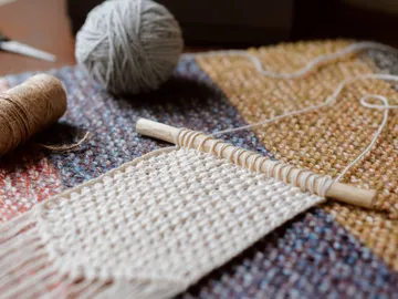 Wool is used on a weaving frame in an artisanal context.