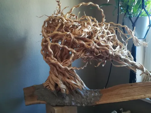 Ein verworrener Baum aus geflochtenem Material steht auf einem Block.