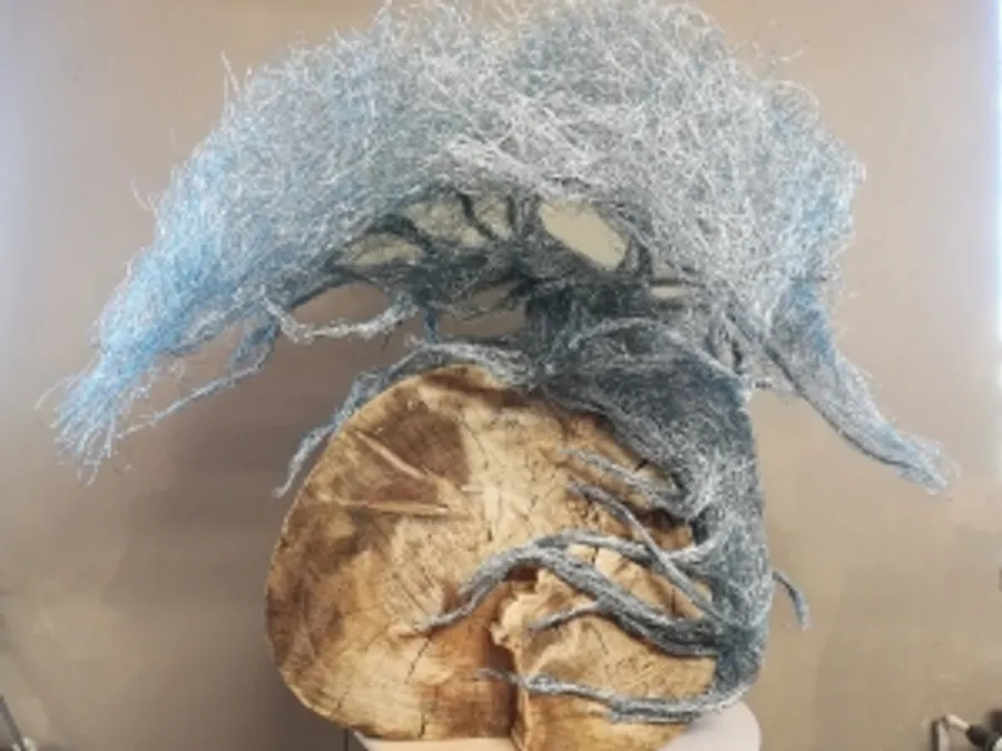 A piece of wood with blue, wire-like tree branches at the top.