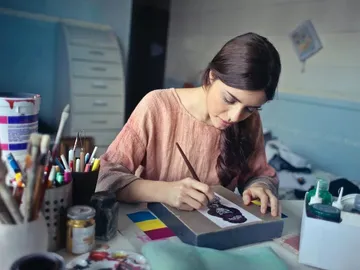 Woman concentrates on a table with materials.