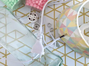The glass bottle and cable lie on a patterned surface.