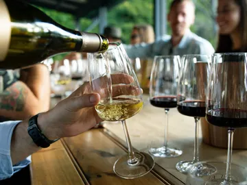 Weißwein wird in ein Glas während einer geselligen Versammlung eingeschenkt.