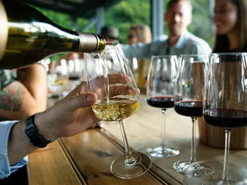 A glass is filled with wine, surrounded by guests.