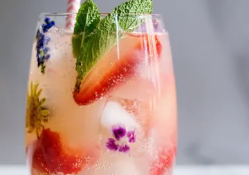 A drink with fruit and flowers in a glass.