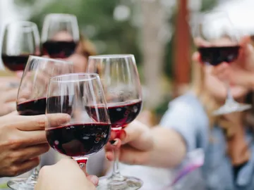 Gläser mit Rotwein werden zum Anstoßen erhoben.