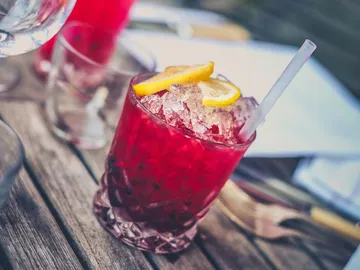 A drink with ice, lemon, on a wooden table.