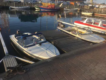 Zwei Boote liegen an einem Holzsteg im Hafen.