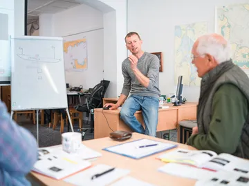 A man is explaining something at a table in a meeting room.