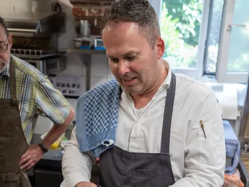 Koch prepared food in a bright kitchen.