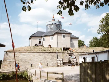 A historic building stands on a hill; people are walking.