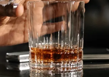 Ein Glas mit Getränk wird von einer Hand gehalten.