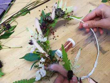 Blumenkranz wird mit einer Hand dekoriert auf Tisch.