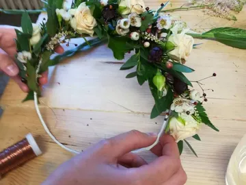 Hand hält einen Blumenkranz, während er dekoriert wird.