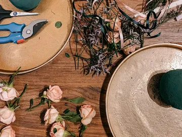 Blumen und Werkzeuge liegen auf einer goldenen Oberfläche.