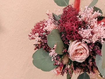 Ein Blumenstrauß zeigt rosa Rosen und getrocknete Pflanzen.