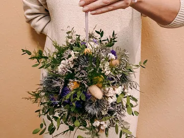 Blumenkranz wird von einer Hand gehalten, dekorativ angeordnet.