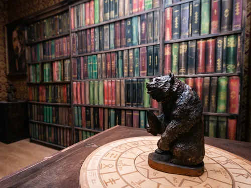 Bärstatue steht auf einem Tisch vor Bücherregalen.