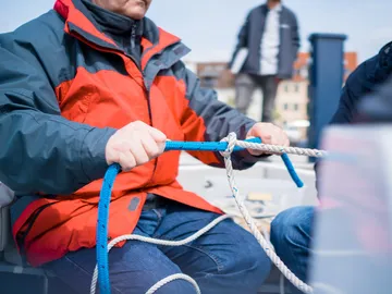 A man ties ropes on an outdoor boat.