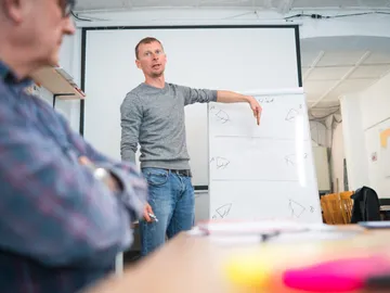 Instructor explains diagram on a whiteboard during a workshop.