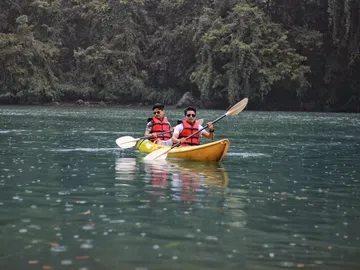 Two men are rowing in a kayak on calm water.