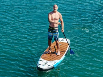 Man paddles in water on a stand-up paddle board.