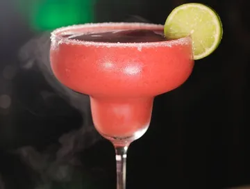 Pink margarita with lime slice, on a dark background.