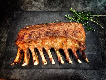 Lamb ribs are lying on a table, decorated with thyme.