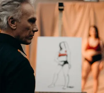 Man looks at a drawing of a modeling person in the background.