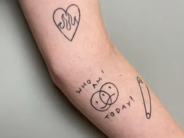 Tattoo on one arm shows symbols and text.