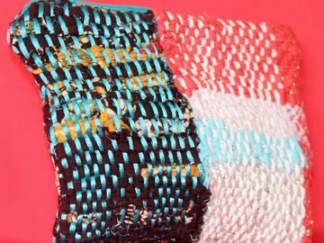 Buntes Gewebe liegt auf rotem Hintergrund, texturiert und gemustert.