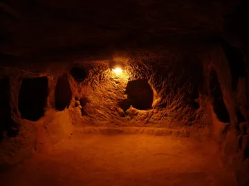 Dunkle Höhle mit sanfter Beleuchtung und unregelmäßigen Wänden.