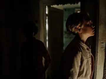Boy looks carefully at the wall in a dark room.