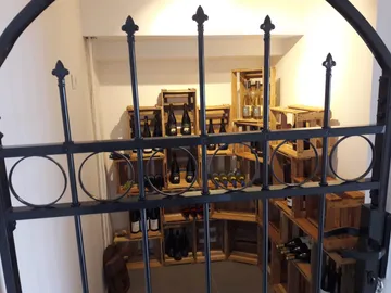 Eisenzaun schützt einen Weinkeller mit Holzkisten.