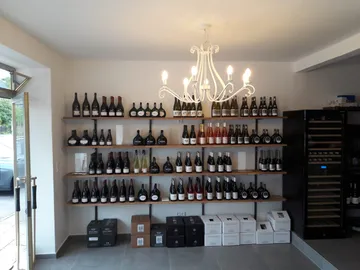 Shelf with wine bottles illuminated by a chandelier.