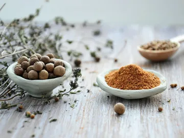 Spices in bowls surrounded by dried herbs.