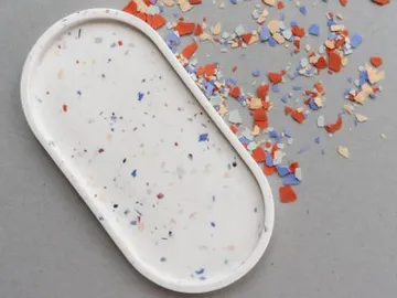 Ein ovales Tablett umgeben von bunten, zerbrochenen Stückchen.