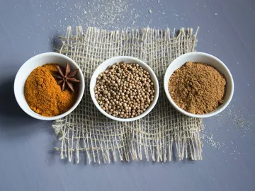 Three bowls of spices arranged on a fabric background.