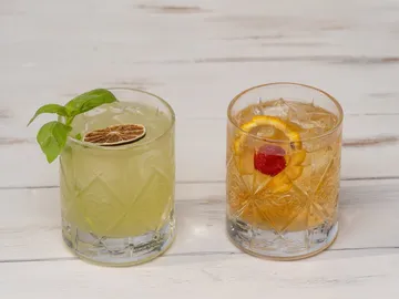 Two cocktails are sitting on a wooden background.