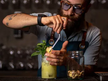 Bartender prepares cocktails with fresh ingredients at the bar.