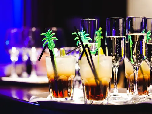 Cocktails mit Ananas-Strohhalmen stehen auf einem Tablett.