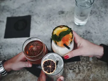 Three cocktails are toasted at a table.