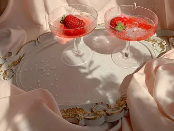 Zwei Gläser mit Erdbeeren auf einem eleganten Tablett.