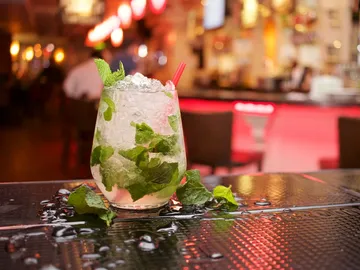 Cocktailglas mit Minze und Eis auf dem Bartisch.