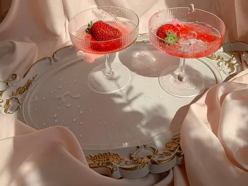 Two glasses with strawberries and drink on a tray.