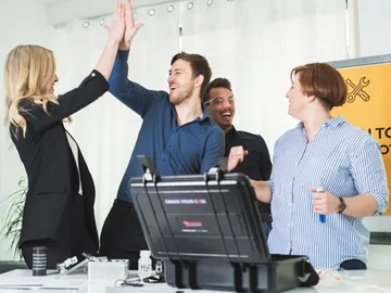 Team is celebrating with a high-five in an office. Happiness and success.