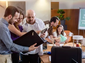 Five people are discussing documents at a conference table.
